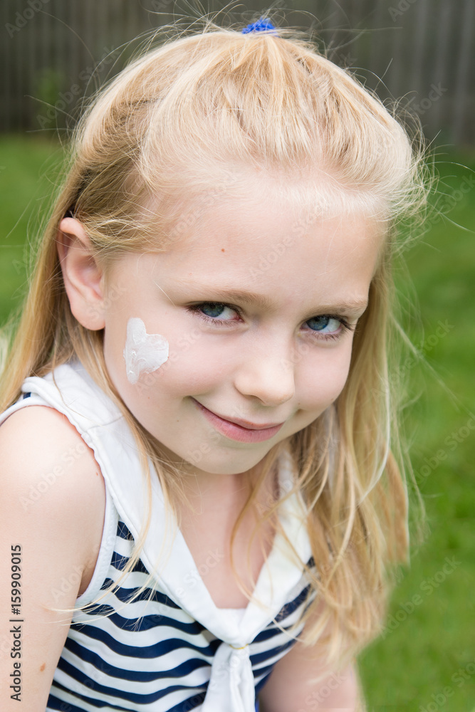 adorable school age girl with sunscreen in heart shape on face outside in summertime adorable school age girl with sunscreen in heart shape on face outside in summertime
