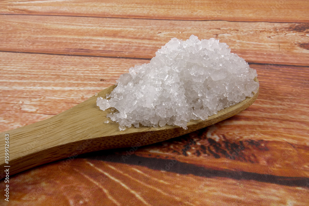 Sea salt in a wooden spoon. Also called bay salt or solar salt, is used in cooking and cosmetics. Rough grained crystals of the mineral. Sea salt in a wooden spoon. Also called bay salt or solar salt, is used in cooking and cosmetics. Rough grained crystals of the mineral.