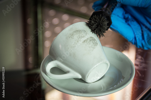 Female forensic scientist finds fingerprints on the cup of coffee
