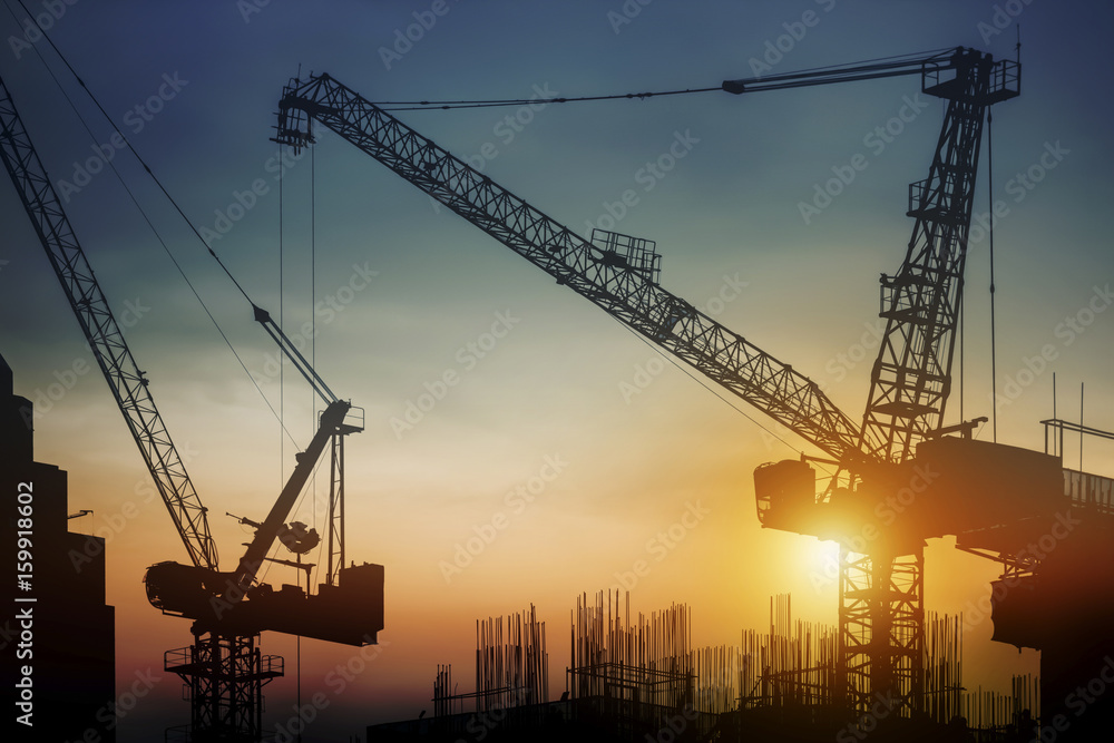 Silhouette construction site with cranes at sunset