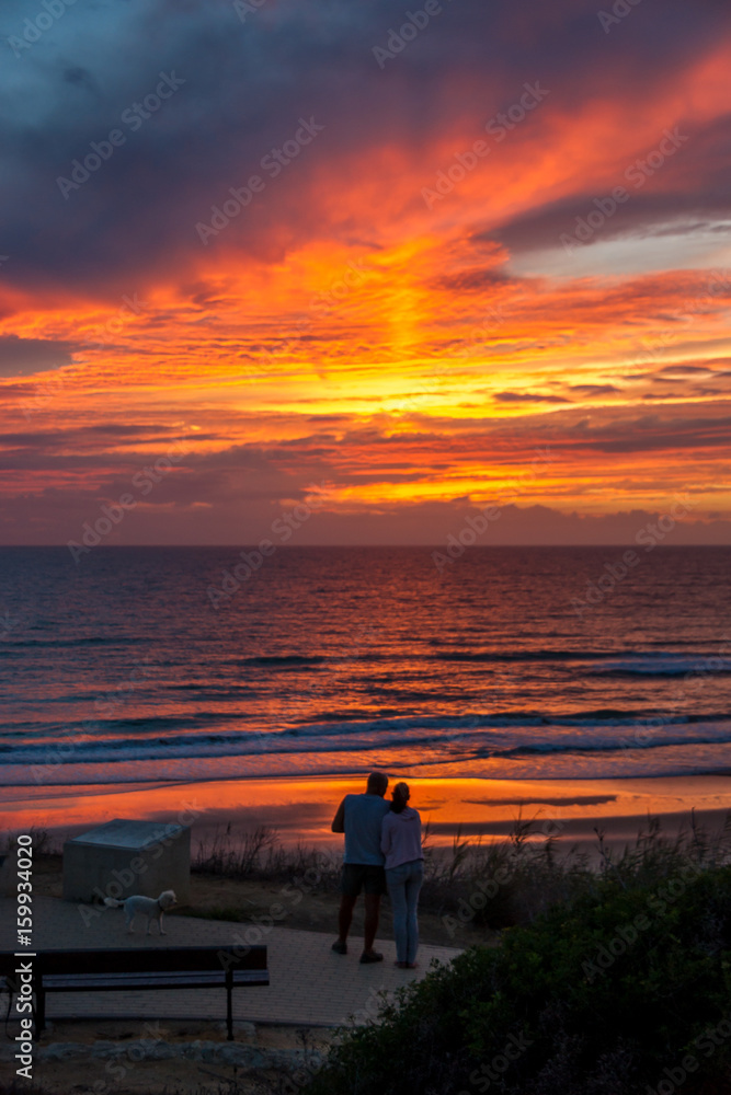 Ein Pärchen genießt einen romantischen Sonnenuntergang am Meer