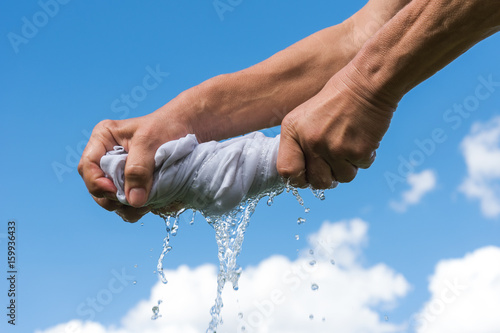 Hands squeeze wet cloth.