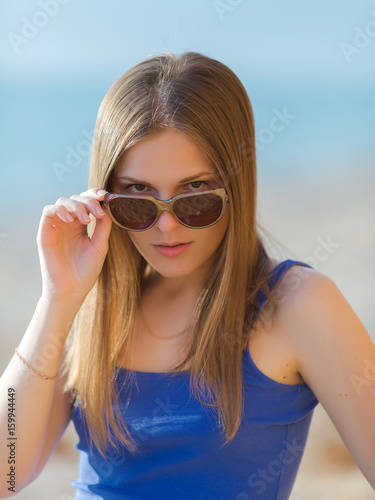 Young woman in blue looking at camera over sunglasses