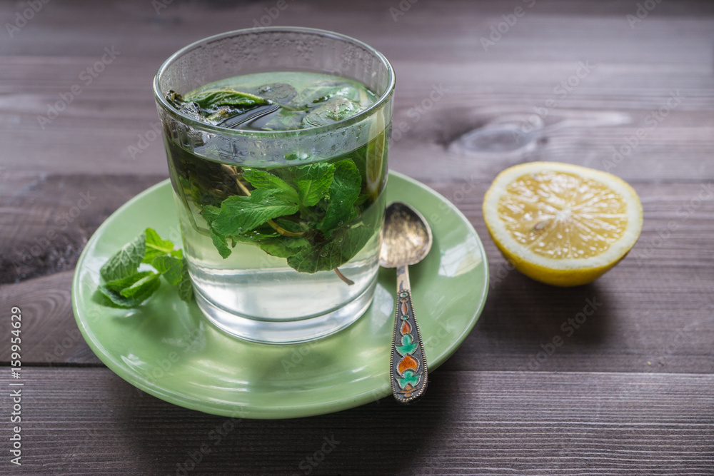 glass of tea with mint and a lemon on a dark table glass of tea with mint and a lemon on a dark table