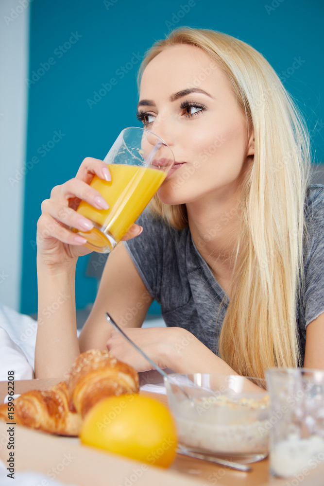 Pretty young blonde woman enjoying a breakfast of fresh crisp croissant and coffee in bed Pretty young blonde woman enjoying a breakfast of fresh crisp croissant and coffee in bed
