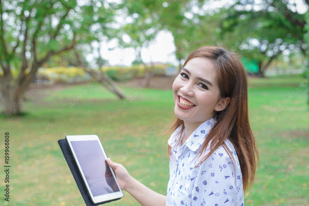 Cheerful woman with beautiful smile play tablet in the park,bright,clear tone Cheerful woman with beautiful smile play tablet in the park,bright,clear tone