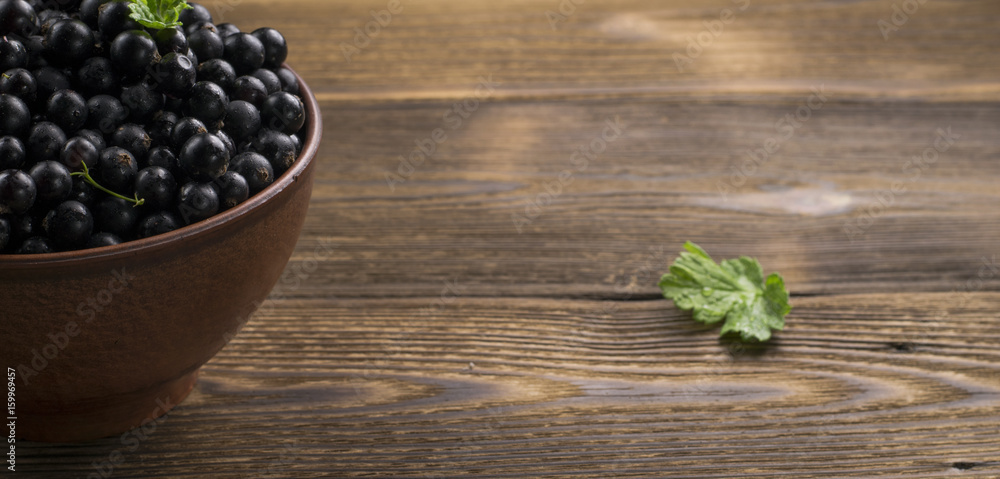 Black currant on wooden table with leaf sprig Black currant on wooden table with leaf sprig