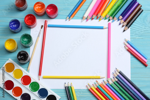 school and office supplies. school background. colored pencils, pen, pains, paper for school and student education on blue wood background. top view with copy space