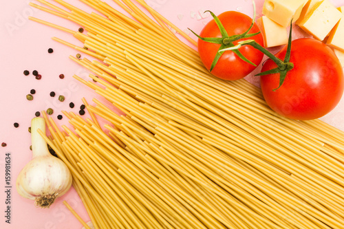 Pasta spaghetti, vegetables and spices, isolated on pink background.