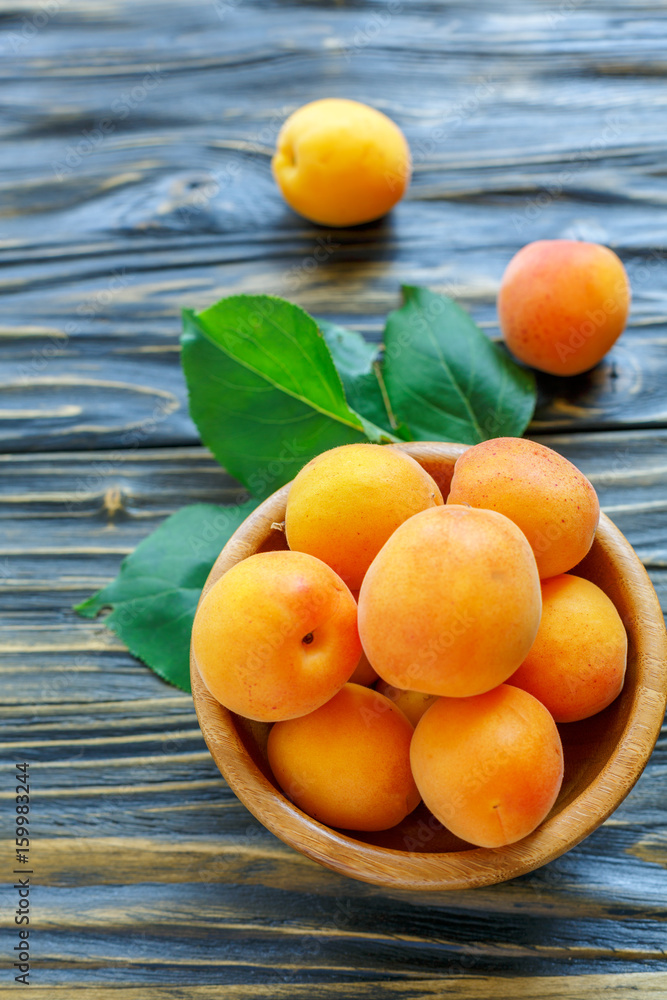 Ripe apricots in a wooden bowl.
