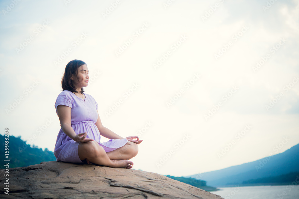Pregnant woman sit on the rock for play yoga side dam,vintage style,pastel tone,dark,film