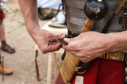 Roman soldier fastens war belt
