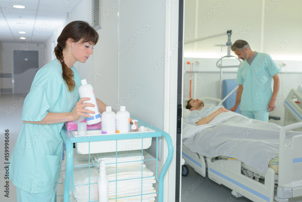 female nurse tiding up trolley in hospital hallway female nurse tiding up trolley in hospital hallway