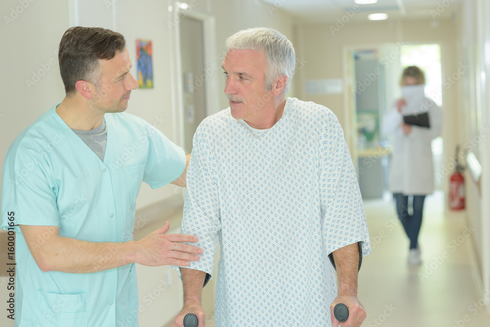 Fototapeta premium male doctor is helping older patient with crutches