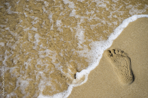 Sand footprint and wave/Image of footprints in the sand on a beach shore at the Black Sea and a wave about to wash them off.