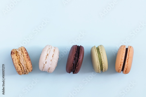 Row of colorful french macaroons on blue background. Top view, copy space for text. Social media, blogging concept 