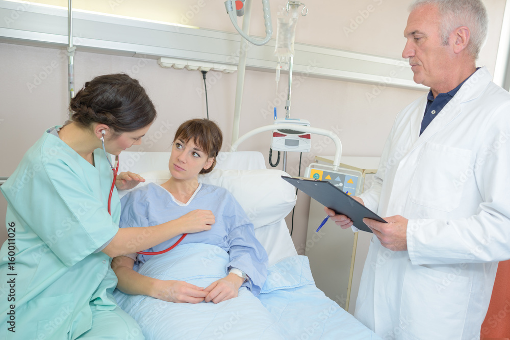 doctos checking on young patient lying in bed hospital doctos checking on young patient lying in bed hospital