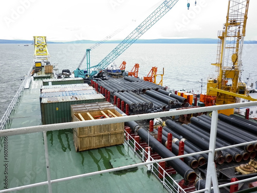 The deck lay barge. Pipes and Lifting cranes on the ship. Equipment for laying a pipeline on the seabed