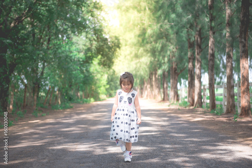 Closeup Touchy little cute girl on the road with the surrounding pine trees,bright sunlight,sweet tone,pastel style