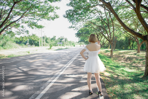 Beautiful thai woman in white dress gold hairs stand on the road,She was waiting for someone to get her back © reewungjunerr