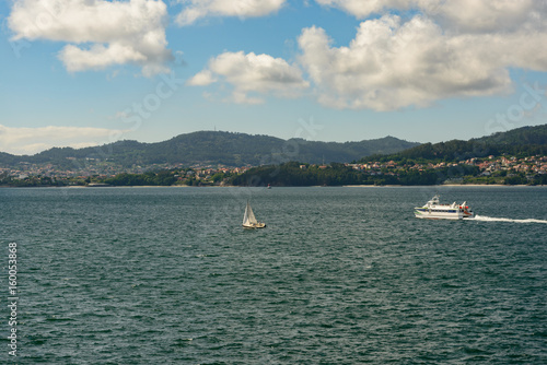 View of Vigo, Spain from the ocean on a clear day in spring with a sailboat and a ferry   © clsdesign