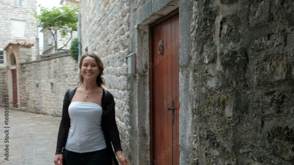 Attractive woman with interest examines a narrow street. Tourist walks in the old town and the European arm touches knoker. Door ring knock installed above the door. Beautiful lady with delight looks Attractive woman with interest examines a narrow street. Tourist walks in the old town and the European arm touches knoker. Door ring knock installed above the door. Beautiful lady with delight looks