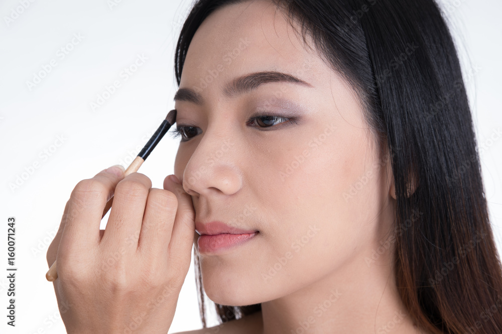 Make-up artist applying brown color eyeshadow make up on model's eye Make-up artist applying brown color eyeshadow make up on model's eye