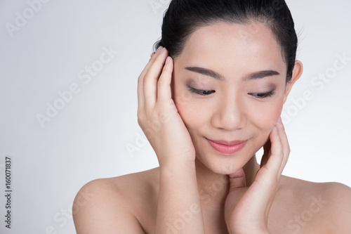 Portrait of a smiling young woman with natural make-up. beautiful asian girl standing against white background. Skincare, healthcare, studio shot.