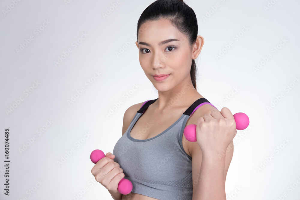 Young asian sporting woman training with dumbbell. Pretty athletic girl making physical exercise against white background. Healthy lifestyle concept.