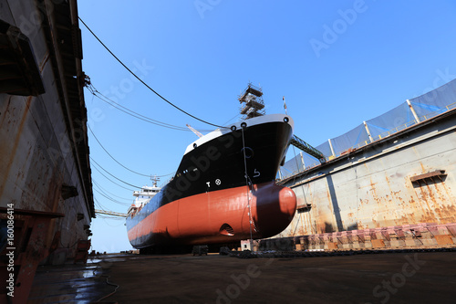 Oil tanker vessel black color on top and red color down below on dry dock to do repair