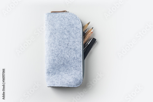 Fotografiet Top view of grey fabric pencil case with lot of pens on white background desk fo