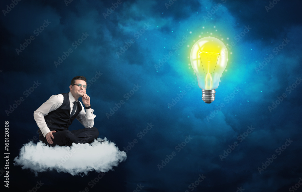 Man sitting on cloud looking at a lightbulb