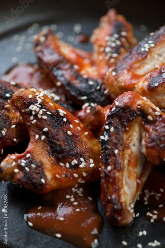 Close-up of bbq chicken wings with sesame seeds and tomato sauce, selective focus, vertical shot