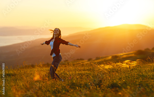 Happy woman dances, rejoices, laughs on sunset in nature