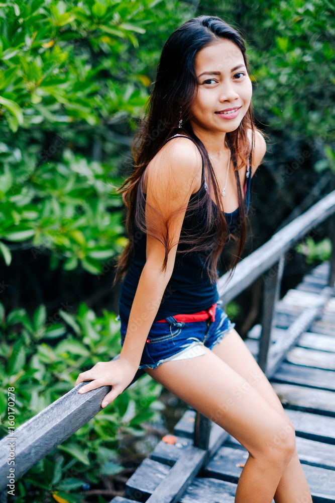 Young beautiful girl portrait on the wooden bridge in the mangrove forest Young beautiful girl portrait on the wooden bridge in the mangrove forest