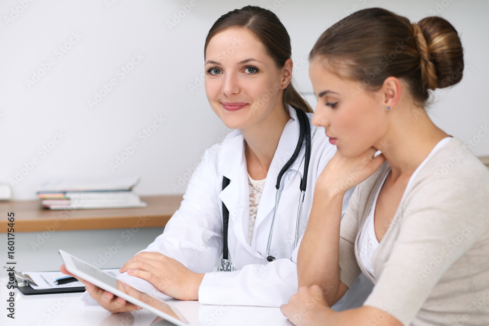 Doctor and patient sitting at the desk. Physician pointing into laptop computer. Medicine and health care concept Doctor and patient sitting at the desk. Physician pointing into laptop computer. Medicine and health care concept
