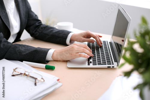 Close up of business woman  hands  typing on  laptop computer in the white colored office.