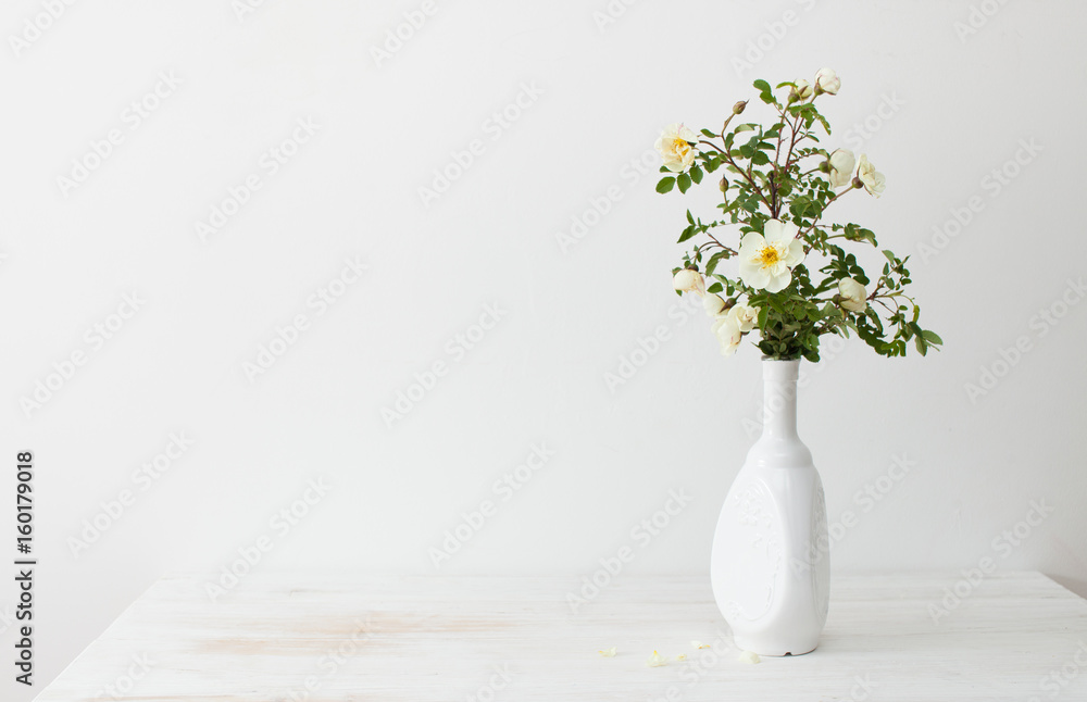 Garden roses in a white vase on a table Garden roses in a white vase on a table
