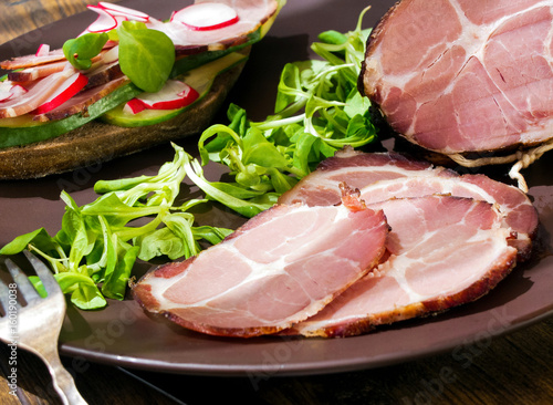 Smoked ham with herbs (dill, lettuce) on wooden board