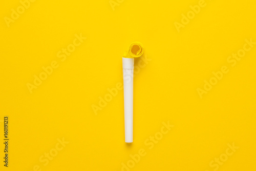paper and plastic party horn on the yellow background
