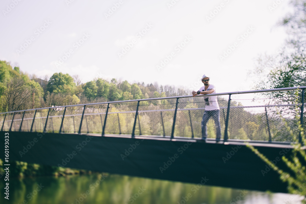 Cooler junger Mann mit Sonnenhut auf Brücke