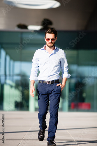 Mann mit Sonnebrille und Hemd im Gehen