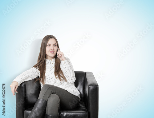 Young woman on phone in an armchair, blue