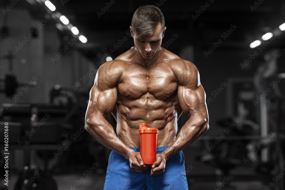 Muscular man in gym with shaker, shaped abdominal. Strong male naked torso abs, working out Muscular man in gym with shaker, shaped abdominal. Strong male naked torso abs, working out