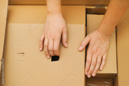 Two woman hands unpacking big cardboard box