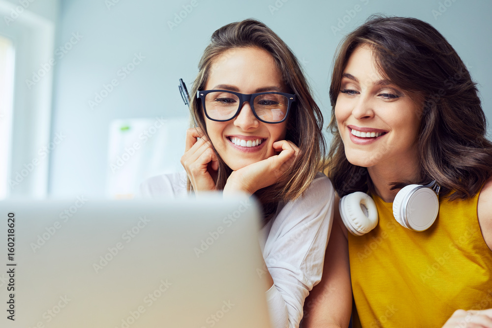 Closeup of two female friends surfing internet on a laptop Closeup of two female friends surfing internet on a laptop