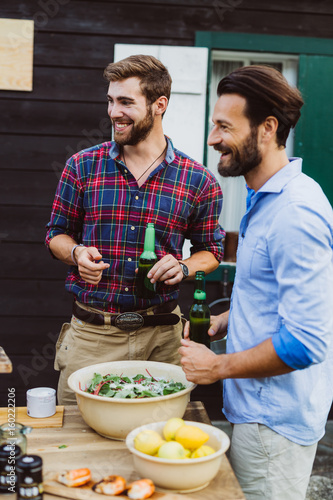 Two men with beear outdoors barbecue