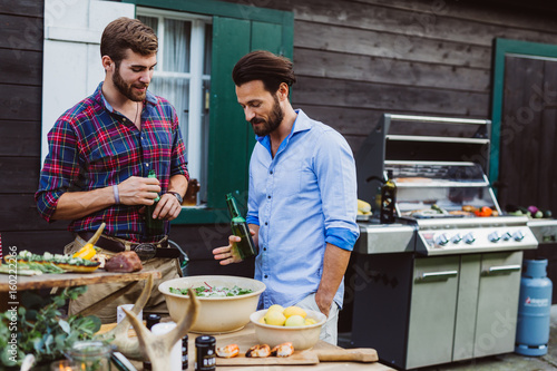 Two men with beear outdoors barbecue