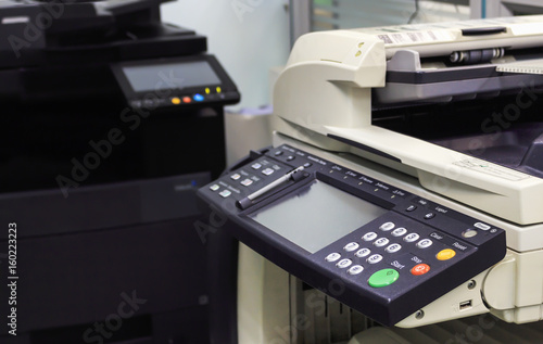 multifunction printer in office with soft-focus and over light in the background