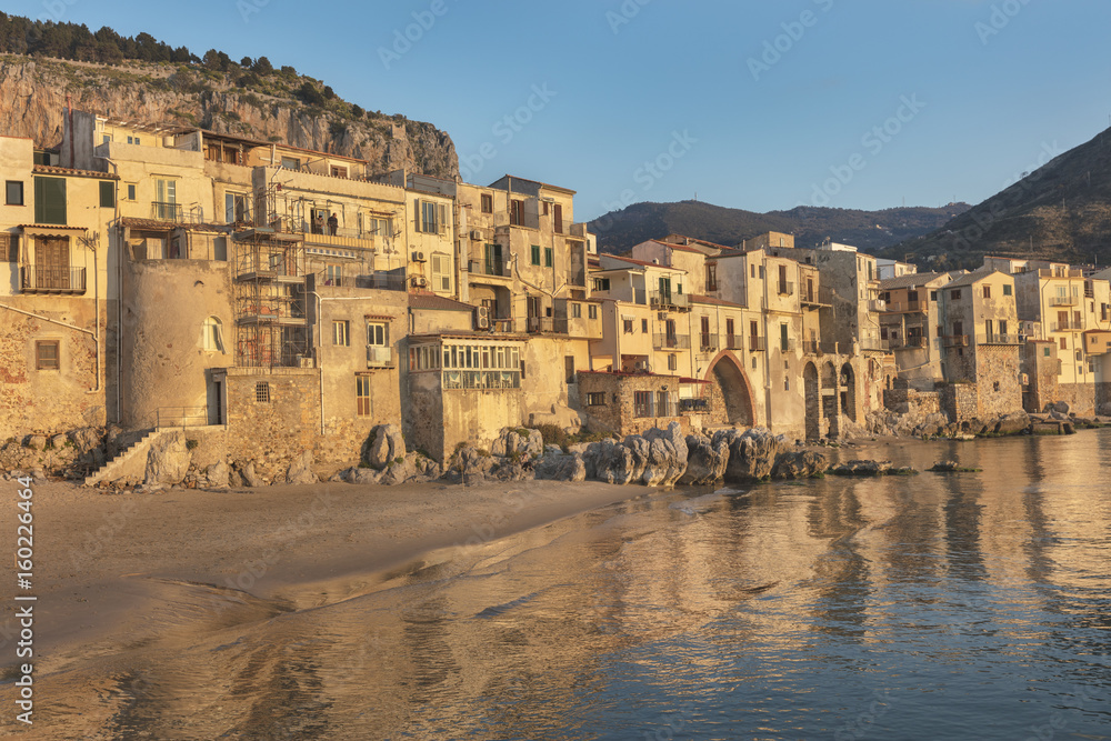 Old houses with reflections in water in late afternoon, Cefalu, Sicily, Italy
